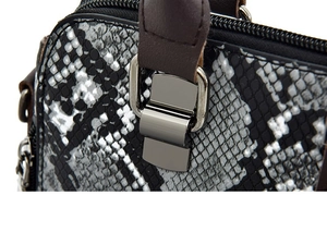 Detail of black and white snakeskin texture with dark brown leather handle and silver buckle