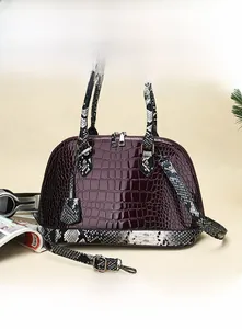 Close-up of wine red crocodile embossed leather shell bag with snake pattern straps
