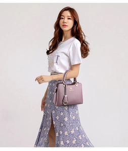 Details einer eleganten lila Lederhandtasche mit goldenem Känguru-Logo und Rundgriff