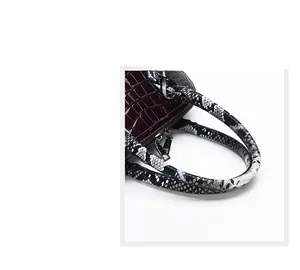 Detail of burgundy crocodile embossed handbag with snake skin handle and dual metal zippers