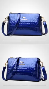 Close-up of deep blue patent leather handbag with crocodile texture and gold hardware