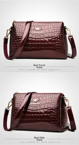 Detail of wine red patent leather shoulder bag with crocodile pattern and golden logo