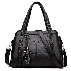Black leather tote bag with V-shaped stitching, woven handle and a grey tassel charm