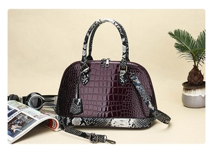 Macro view of burgundy crocodile embossed leather handbag with python print trim