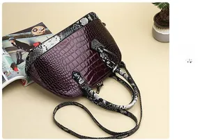 Detail view of burgundy croc-embossed shell bag with black and white snake-print handles