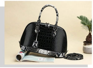 Detail of crocodile pattern texture on shell bag with snake print handle and silver zipper
