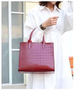 Detail view of red crocodile pattern tote bag with polished texture and round handles