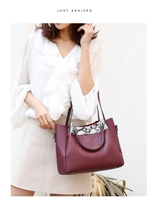 Detail of burgundy crocodile pattern tote bag with snake print trim and dual handles