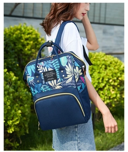 Detail of blue mommy backpack featuring colorful tropical leaf prints and large front pocket