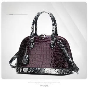 Detail view of burgundy faux crocodile leather handbag with snakeskin pattern texture