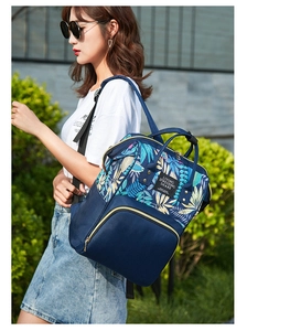Detail of blue multi-functional diaper backpack with tropical leaf print and gold zippers