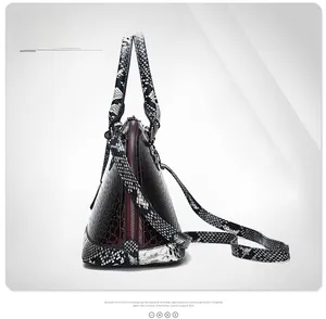 Side view of luxury burgundy crocodile embossed handbag with snake print handle and silver zippers