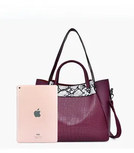 Detail view of burgundy crocodile pattern bucket bag showing its capacity next to an iPad