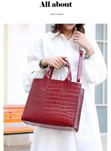 Detail of burgundy crocodile pattern handbag showing glossy texture and metal base studs