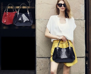 Detail of crocodile embossed tote bag in black and red with gold-tone hardware accents