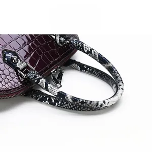 Detail of burgundy crocodile pattern handbag with snake skin handle and silver hardware