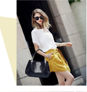 Close-up of black crocodile pattern embossing on a glossy leather handbag for women