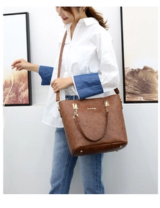 Detail of brown litchi pattern leather tote bag with gold hardware and protective base studs