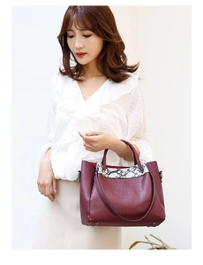 Detail view of burgundy crocodile pattern handbag with snakeskin texture accents