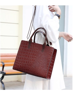 Dark brown crocodile embossed tote bag with high-gloss finish shown in outdoor setting