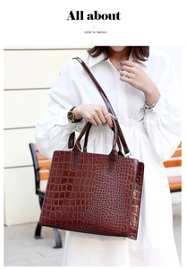 Detail of a brown crocodile embossed tote bag with dual handles and shoulder strap