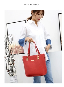 Detail of red faux leather tote bag with gold chain hardware and sturdy double handles