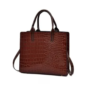 Detail view of large dark brown tote bag with embossed crocodile texture and dual handles