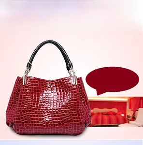 Detail of red crocodile pattern handbag with glossy finish and black braided handles