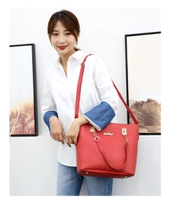 Detail of red leather tote bag with gold logo hardware and adjustable shoulder strap