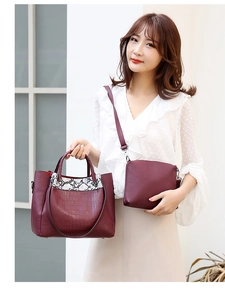 Detail of burgundy crocodile-embossed tote and snakeskin-pattern crossbody bag set