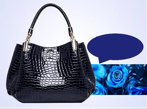 Detail of dark blue crocodile texture handbag with woven handle and gold hardware