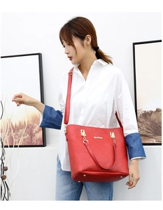 Detail of red faux leather tote bag showing gold logo and adjustable shoulder strap