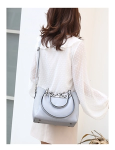 Detail of light blue crossbody bucket bag with snakeskin texture handles on a model