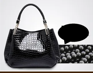 Detail of black crocodile embossed tote bag with woven handles and gold hardware