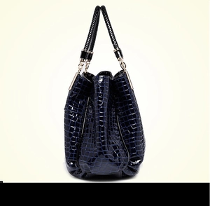 Detail showing high-gloss crocodile embossed leather texture on a navy blue handbag