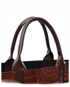 Close-up of brown crocodile pattern handbag with shiny patent finish and durable handle