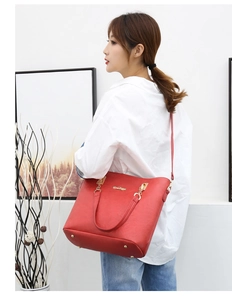 Detailed view of red textured leather tote bag with gold hardware and logo for women