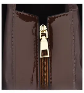 Close-up of smooth gold metal zipper pull and textured brown crocodile pattern fabric