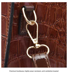 Macro view of gold-tone metal hook hardware on brown crocodile pattern leather handbag