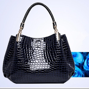 Detail of navy blue crocodile embossed shoulder bag with shiny finish and braided handle