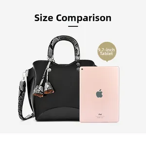 Size comparison of black patent handbag with snake skin straps next to a 9.7 inch tablet