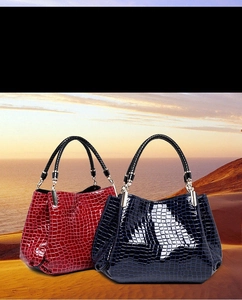 Detail of crocodile pattern patent leather handbags in burgundy and navy blue tones