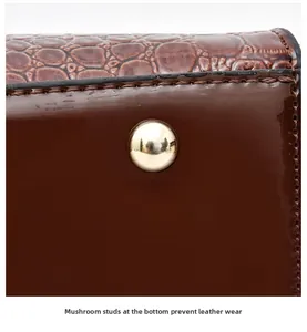 Macro view of brown faux crocodile leather bag bottom with gold protective metal studs