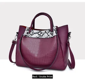 Side view of dark red tote bag with crocodile and snakeskin patterns in macro detail