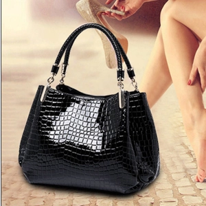 Detail of black faux crocodile pattern leather handbag with glossy patent finish