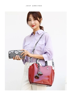 Red patent leather tote bag with snakeskin strap and matching wallet on white background