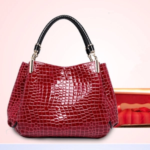 Close-up of red crocodile pattern embossed tote bag with black braided leather handle