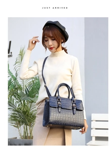 Detail showing deep blue crocodile pattern leather bag with golden metallic hardware