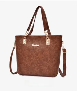 Detailed side view of brown textured leather tote bag with gold logo and shoulder strap