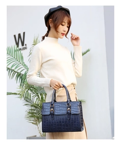 Detail view of the navy blue crocodile pattern embossed handbag with gold hardware buckles